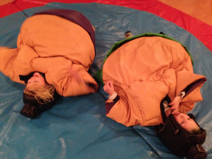 Två ungar som är utslagna efter att ha kört en omgång sumobrottning i våra sumodräkter för barn